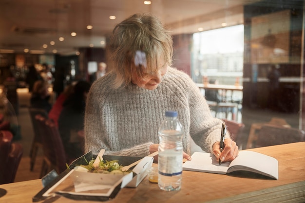 Donna a tiro medio che scrive sul taccuino