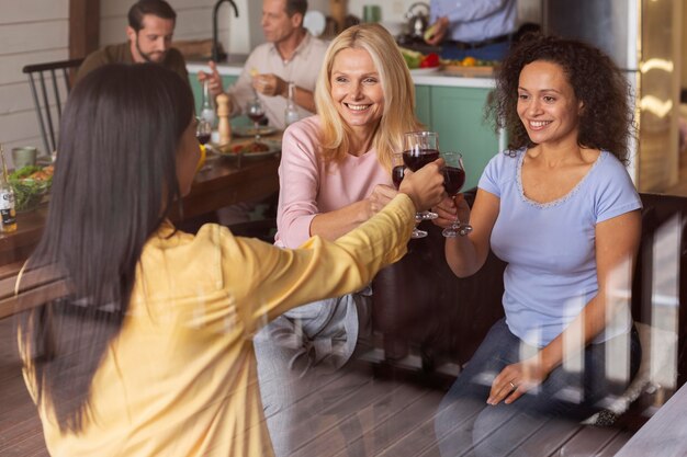 Medium shot women clinking glasses