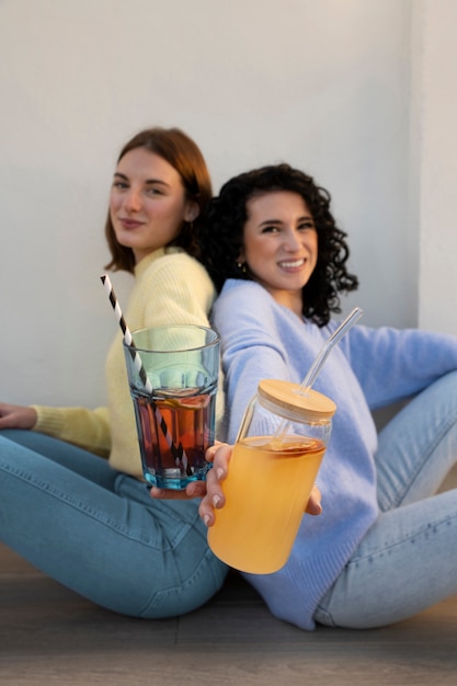 Free photo medium shot women drinking kombucha