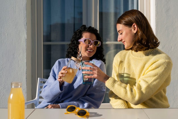 Free photo medium shot women drinking kombucha