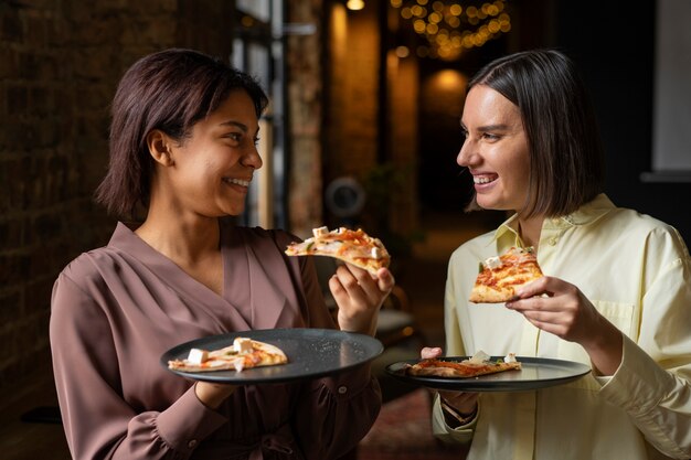 Женщины среднего роста едят вкусную пиццу