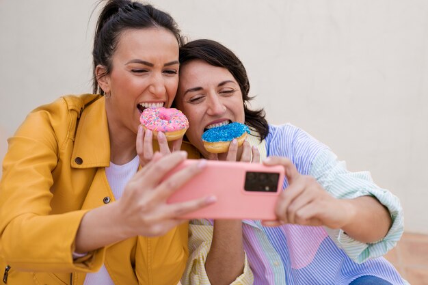 Medium shot women eating doughnuts