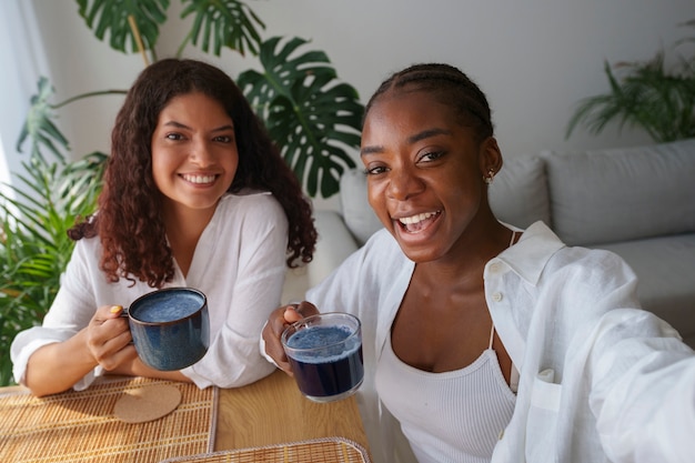 Free photo medium shot women enjoying blue matcha at home