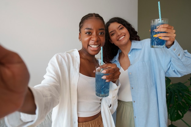 Free photo medium shot women enjoying blue matcha at home