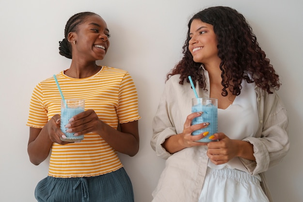 Free photo medium shot women enjoying blue matcha at home