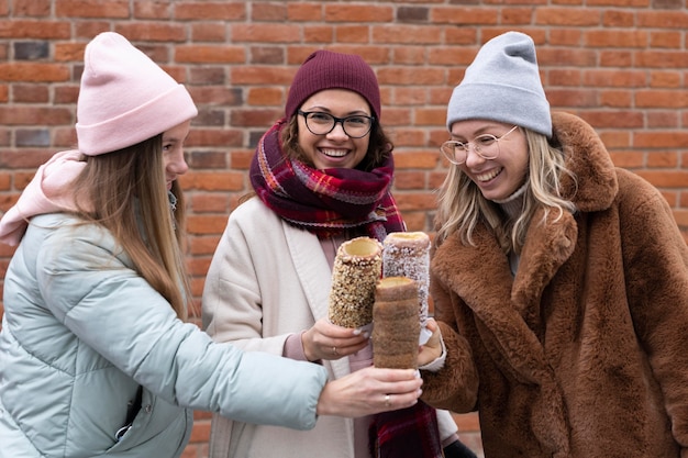 Medium shot women holding chimney cakes