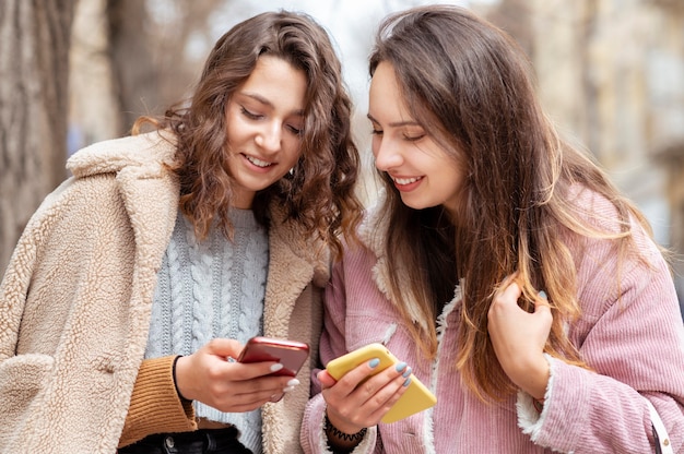 Medium shot women holding smartphones