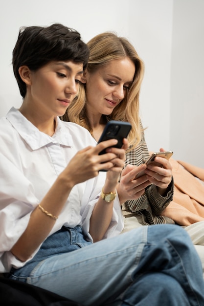 Free photo medium shot women holding smartphones