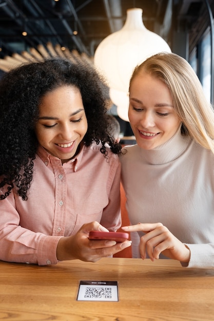 Free photo medium shot women holding smartphones