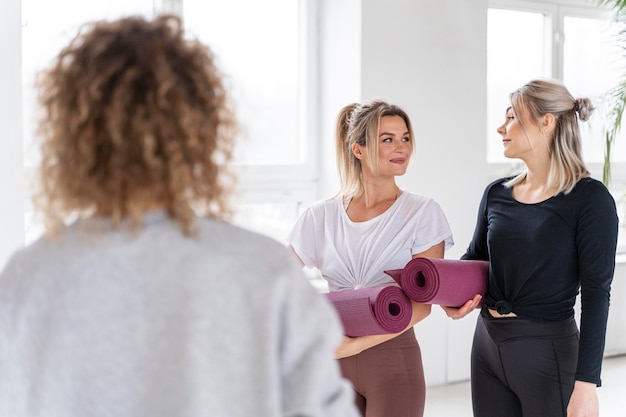 Medium shot women holding yoga mats