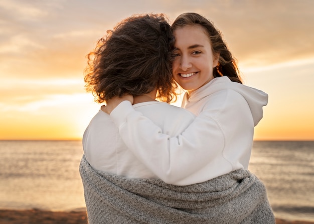 Donne del colpo medio che abbracciano alla spiaggia