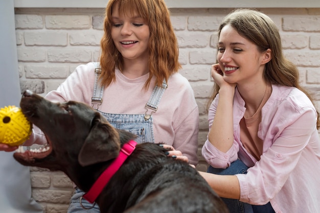 Free photo medium shot women playing with dog