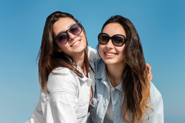 Medium shot women posing with sunglasses