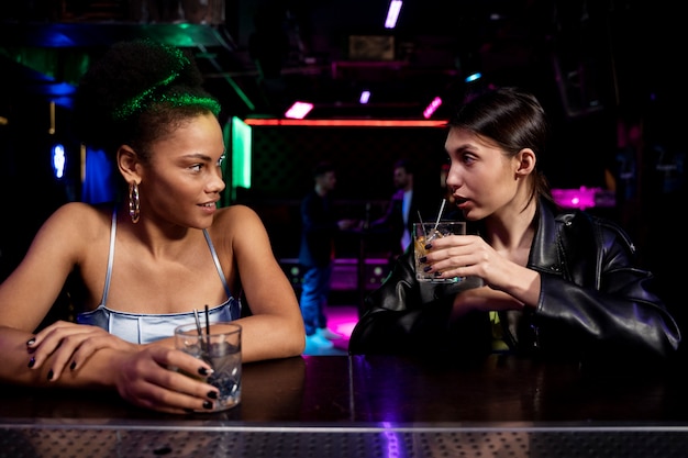 Medium shot women sitting at bar