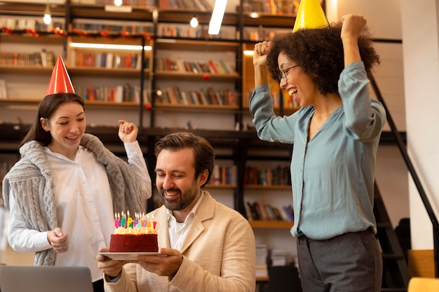 Medium shot women surprising man with tasty cake