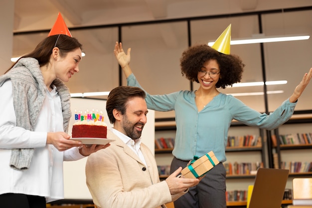 Medium shot women surprising man at work