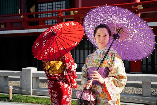 Free photo medium shot women using wagasa umbrella