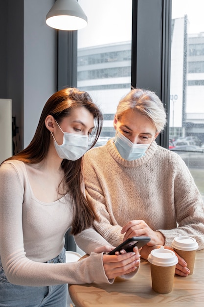 Free photo medium shot women wearing face masks indoors