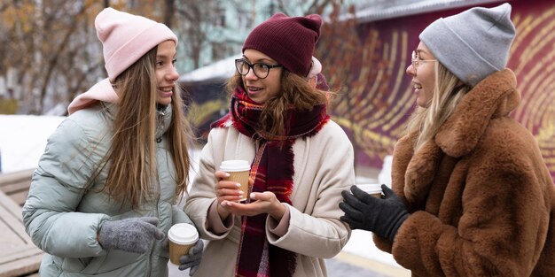 屋外でコーヒーを飲みながらミディアムショットの女性