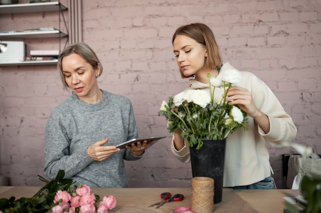 Medium shot women with flower and tablet