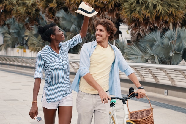 Средний снимок молодой пары, идущей с велосипедом летом