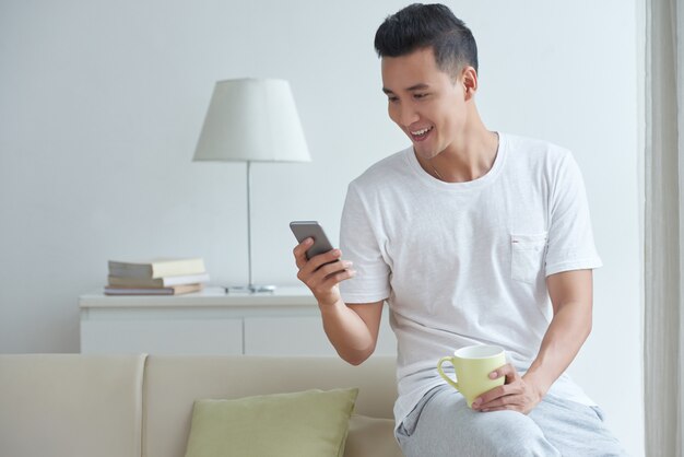 Средний снимок молодой кишки заняты текстовыми сообщениями в его социальных сетях на смартфоне утром