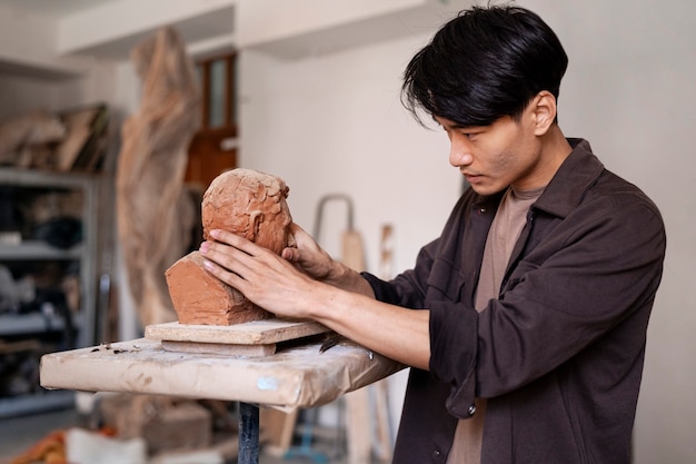 Free photo medium shot young man clay sculpting