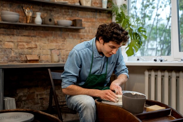 Medium shot young man doing pottery