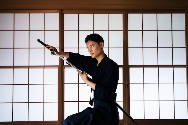 Бесплатное фото Молодой человек среднего роста с самурайским мечом