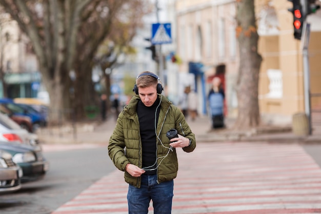 無料写真 外のヘッドフォンで音楽を聴くミディアムショットの若い男