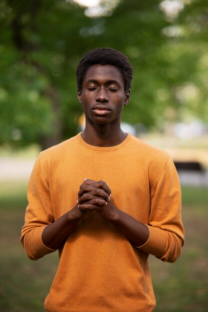 Medium shot young man praying outdoors