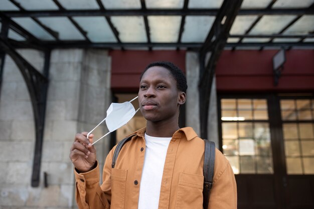 Medium shot young man taking mask off