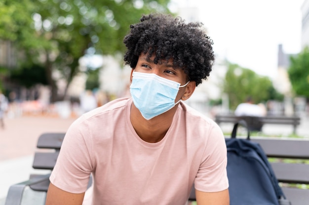 Free photo medium shot young man wearing mask outdoors