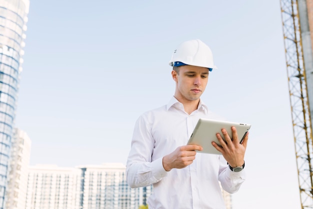 Free photo medium shot young man with helmet and tablet