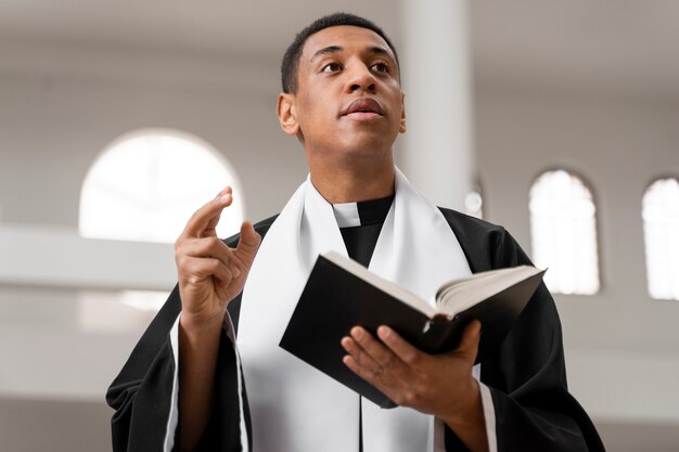 Medium shot young priest holding bible