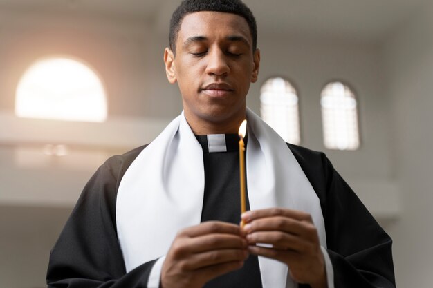 Средний снимок молодого священника со свечой
