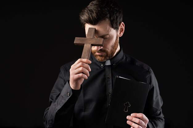 Средний снимок молодого священника с крестом