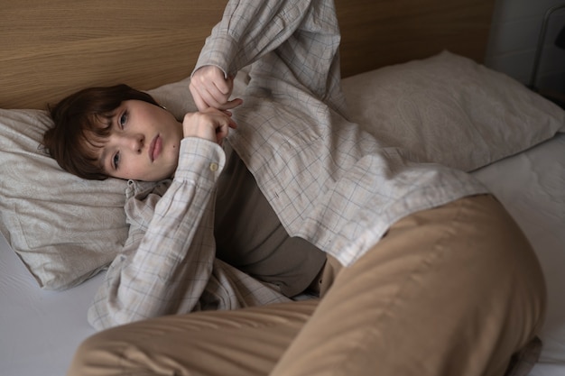 Medium shot young sad woman laying in bed