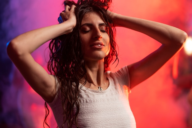 Medium shot young woman dancing at techno party