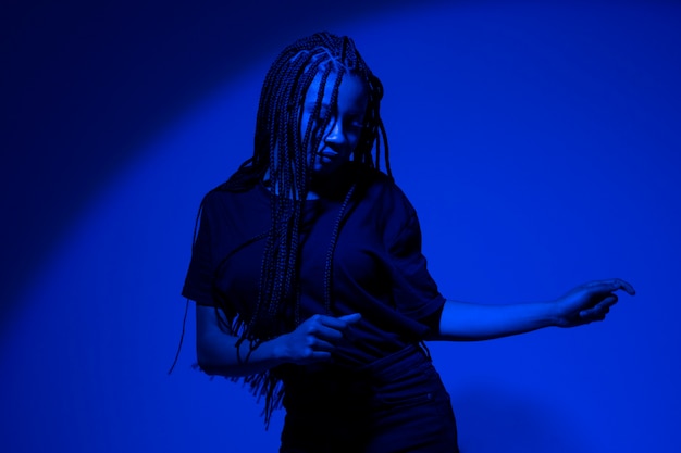 Medium shot young woman dancing with blue light