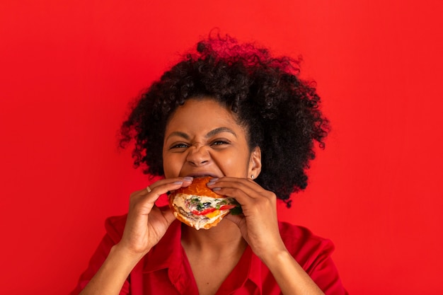 Giovane donna del colpo medio che mangia hamburger