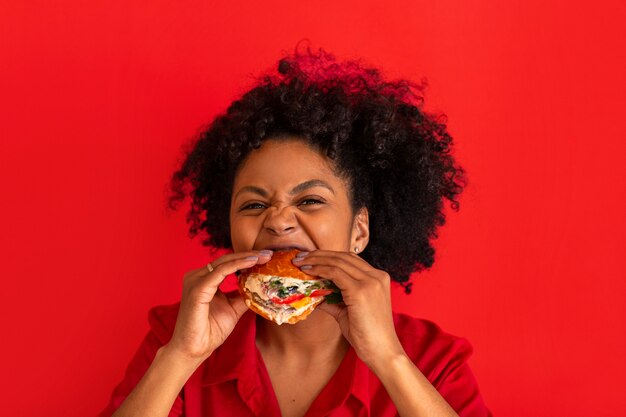 ハンバーガーを食べるミディアムショットの若い女性