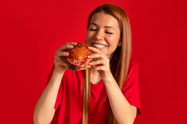 Medium shot young woman eating burger