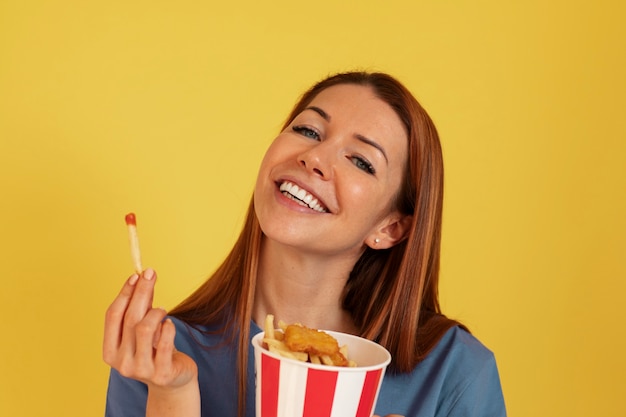 Бесплатное фото Молодая женщина среднего роста ест фаст-фуд