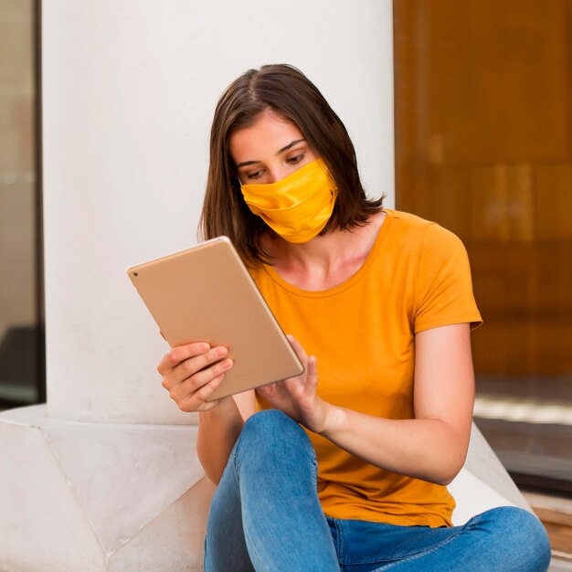 Medium shot young woman holding tablet