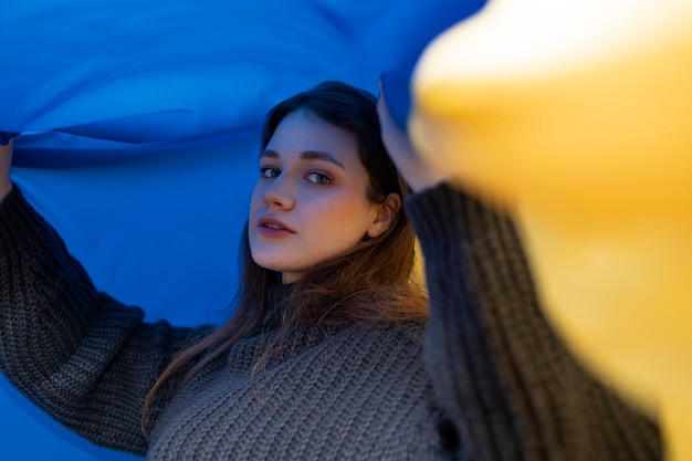 Free photo medium shot young woman holding ukrainian flag