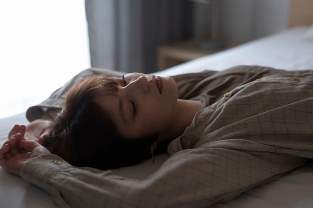 Medium shot young woman laying in bed