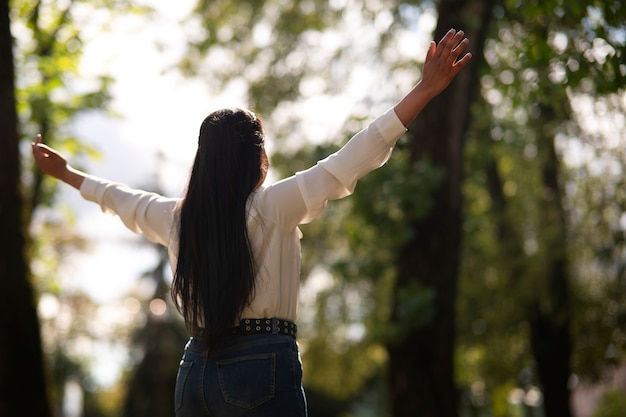 medium shot young woman praying outdoors