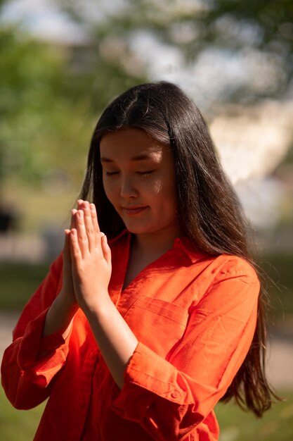 屋外で祈るミディアムショットの若い女性