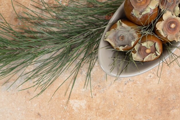 Free photo medlar fruit in bowl with grass on orange table.